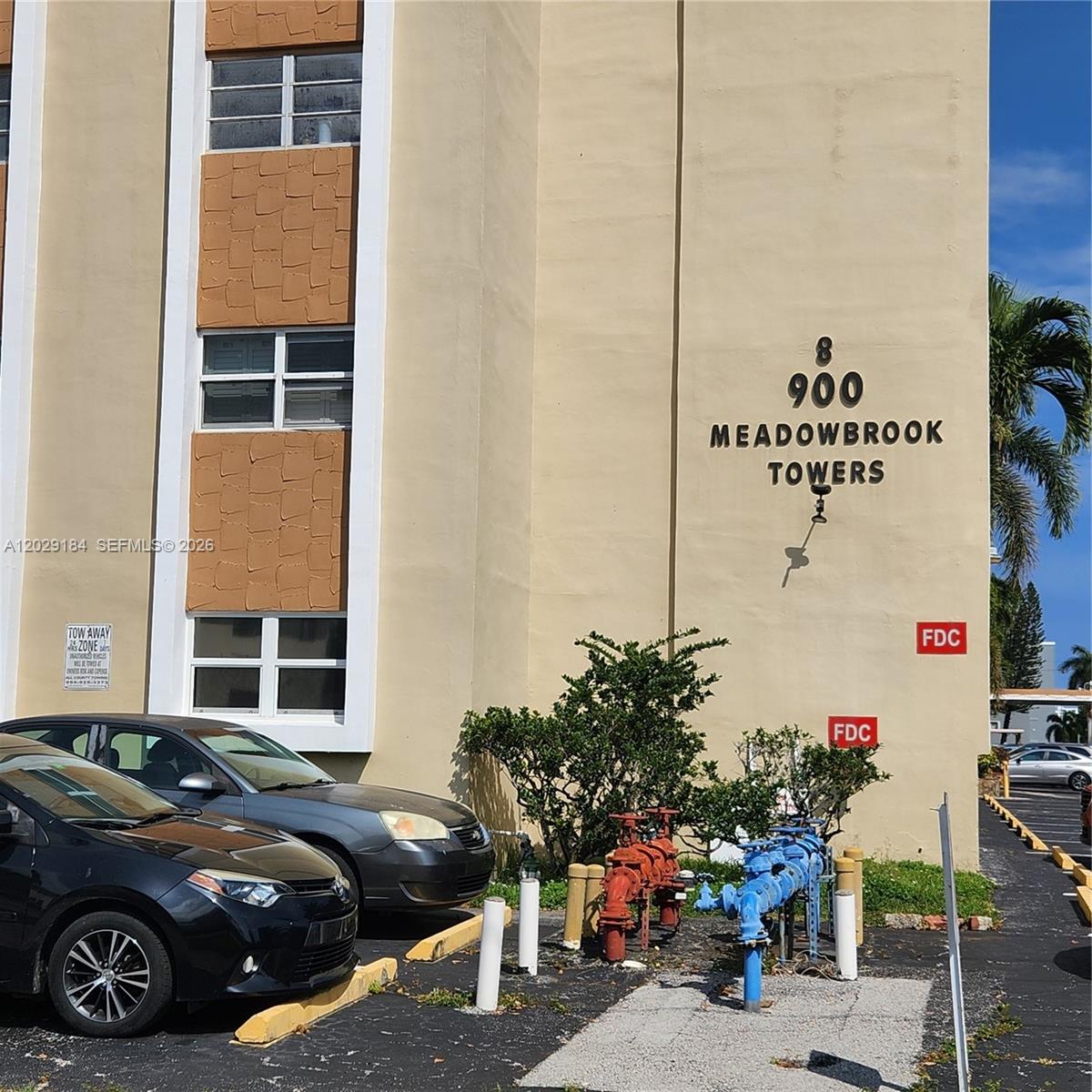 The exterior of a multi-story apartment building features fire department connections and parked cars — 900 NE 12th Ave # 406, Hallandale Beach FL 33009, HALLANDALE BEACH, FL