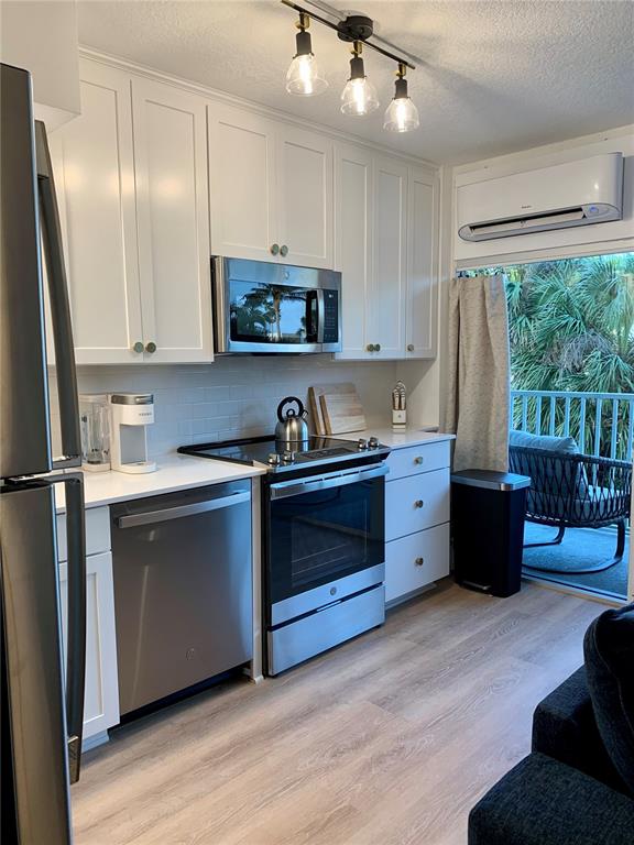 A kitchen with white cabinets, stainless steel appliances, and a balcony view — 800 BAYWAY BOULEVARD UNIT 16, CLEARWATER BEACH, FL