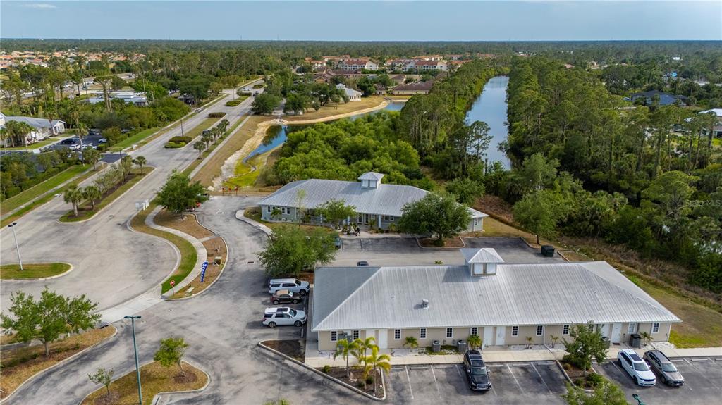 An aerial view shows two commercial buildings with metal roofs, parking lots, and surrounding greenery — 2525 BOBCAT VILLAGE CENTER ROAD, NORTH PORT, FL