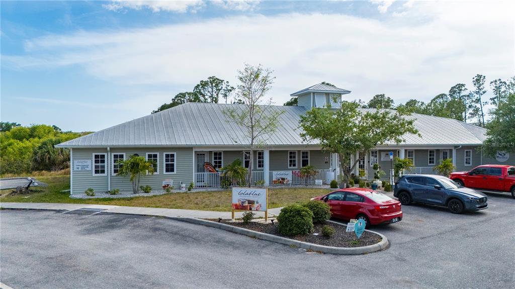 A single-story commercial building with light green siding and a metal roof sits outdoors — 2525 BOBCAT VILLAGE CENTER ROAD, NORTH PORT, FL