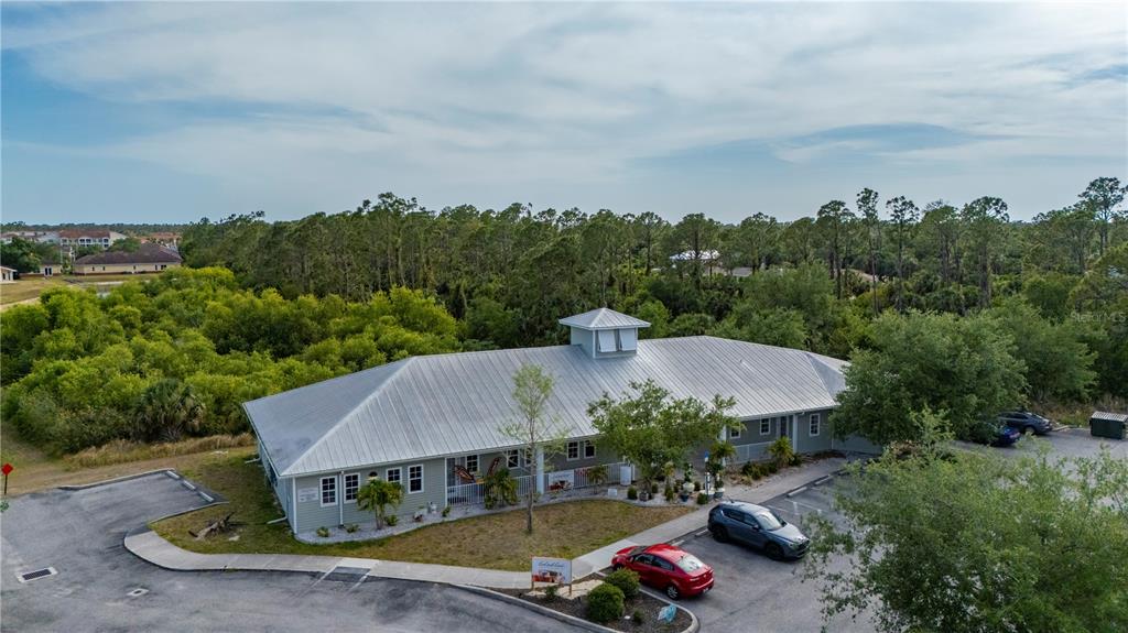 An aerial view shows a single-story commercial building with a metal roof and parking lot — 2525 BOBCAT VILLAGE CENTER ROAD, NORTH PORT, FL
