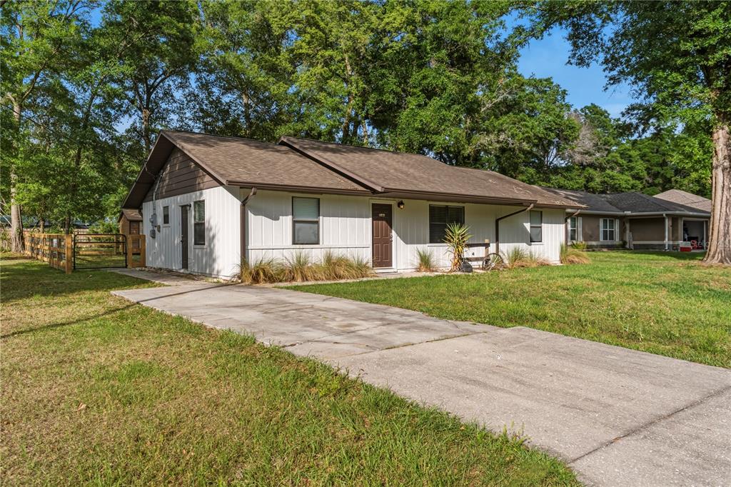 A single-story house with white vertical siding and a brown roof sits on a lawn — 6915 NW 60TH STREET ROAD, OCALA, FL