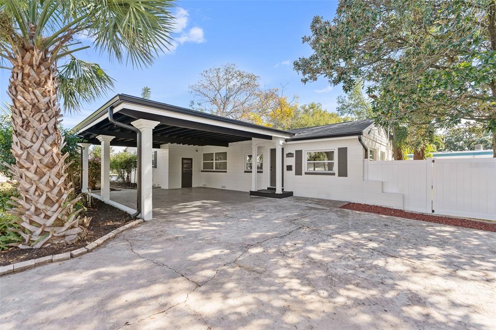 A white single-story house with a black-roofed carport and a large palm tree in front — 2800 E ANDERSON STREET, ORLANDO, FL