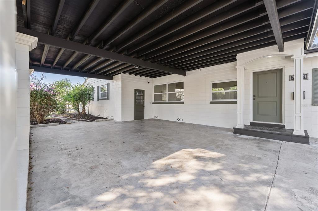 A covered concrete carport area features a white exterior wall and a dark wooden ceiling — 2800 E ANDERSON STREET, ORLANDO, FL