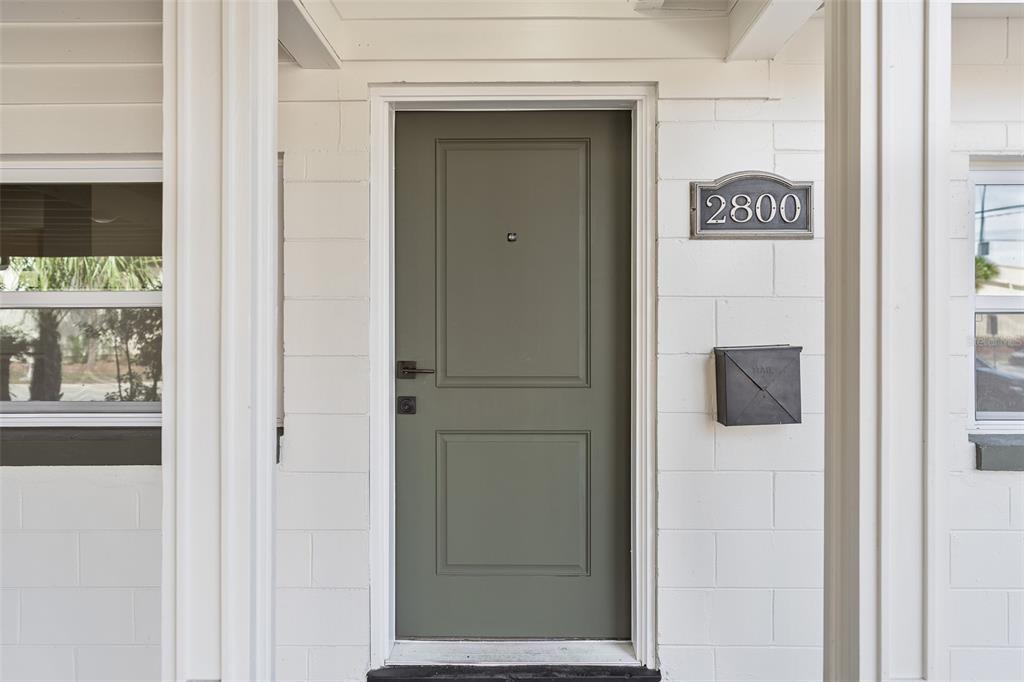 A sage green front door with a black mailbox and house number plaque on white brick — 2800 E ANDERSON STREET, ORLANDO, FL