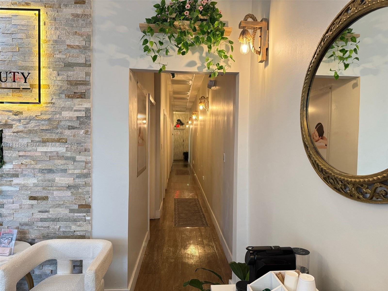 A hallway with wood floors and wall sconces leads from a waiting area with stone accents — 10328 W flagler st, Miami FL 33174, MIAMI, FL