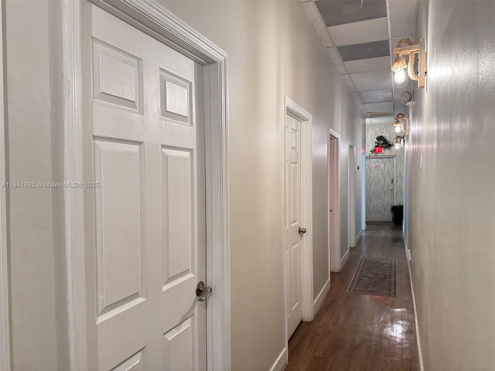 A narrow hallway features wood-look flooring, multiple white doors, and wall-mounted rope light fixtures — 10328 W flagler st, Miami FL 33174, MIAMI, FL