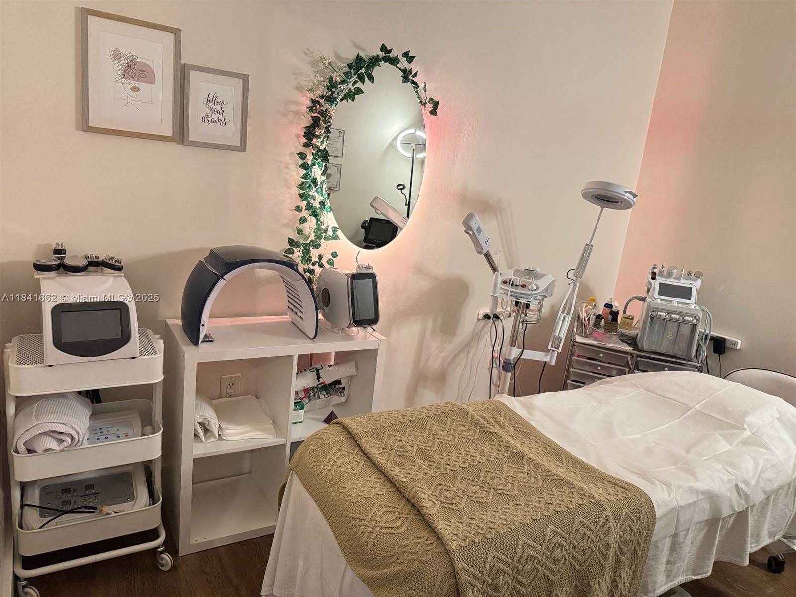 A spa treatment room features a massage table, various aesthetic equipment, and a decorative wall mirror — 10328 W flagler st, Miami FL 33174, MIAMI, FL