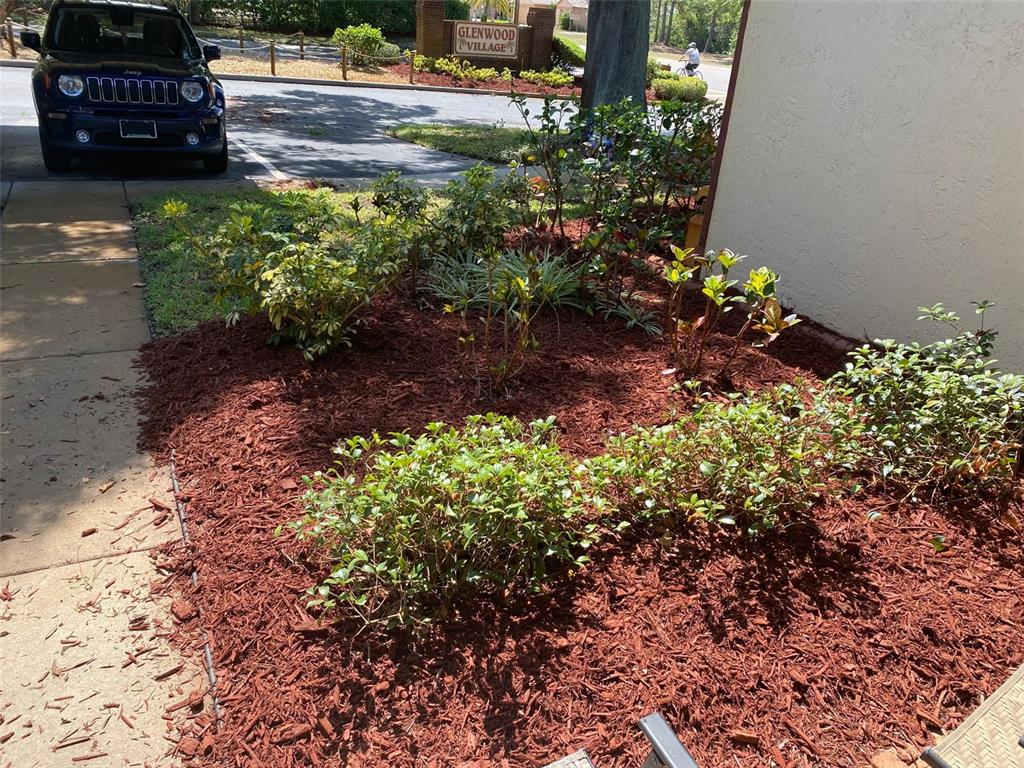 A dark SUV is parked near a landscaped garden bed with red mulch and shrubs — 12539 GREYLOCK LANE, HUDSON, FL