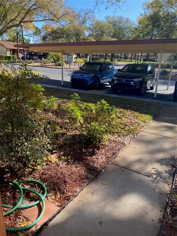 A view of a covered parking area with two cars parked in front of landscaping — 12539 GREYLOCK LANE, HUDSON, FL