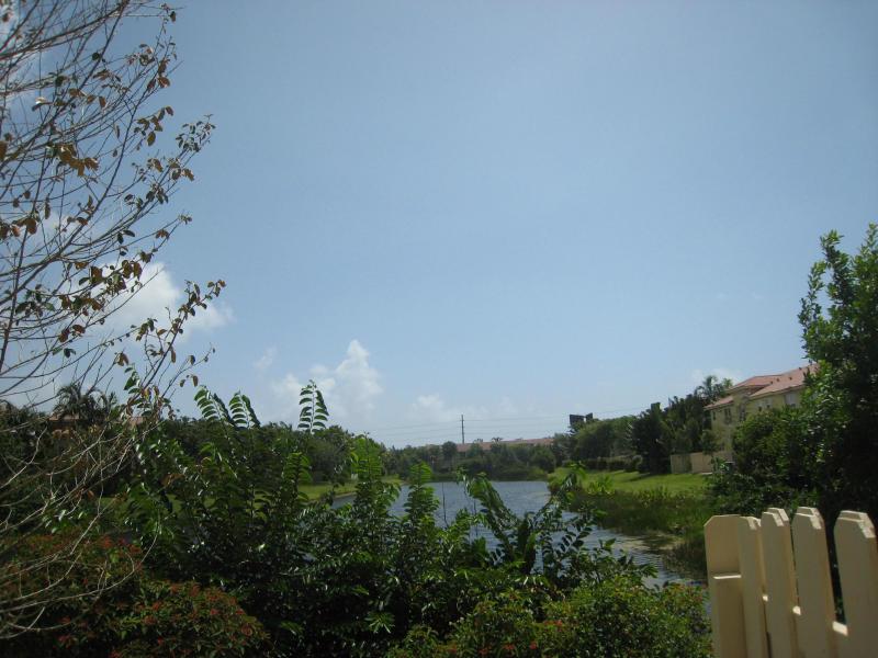 A view of a pond surrounded by trees and houses under a clear blue sky — 138 Monterey Bay Drive, Boynton Beach FL 33426, BOYNTON BEACH, FL