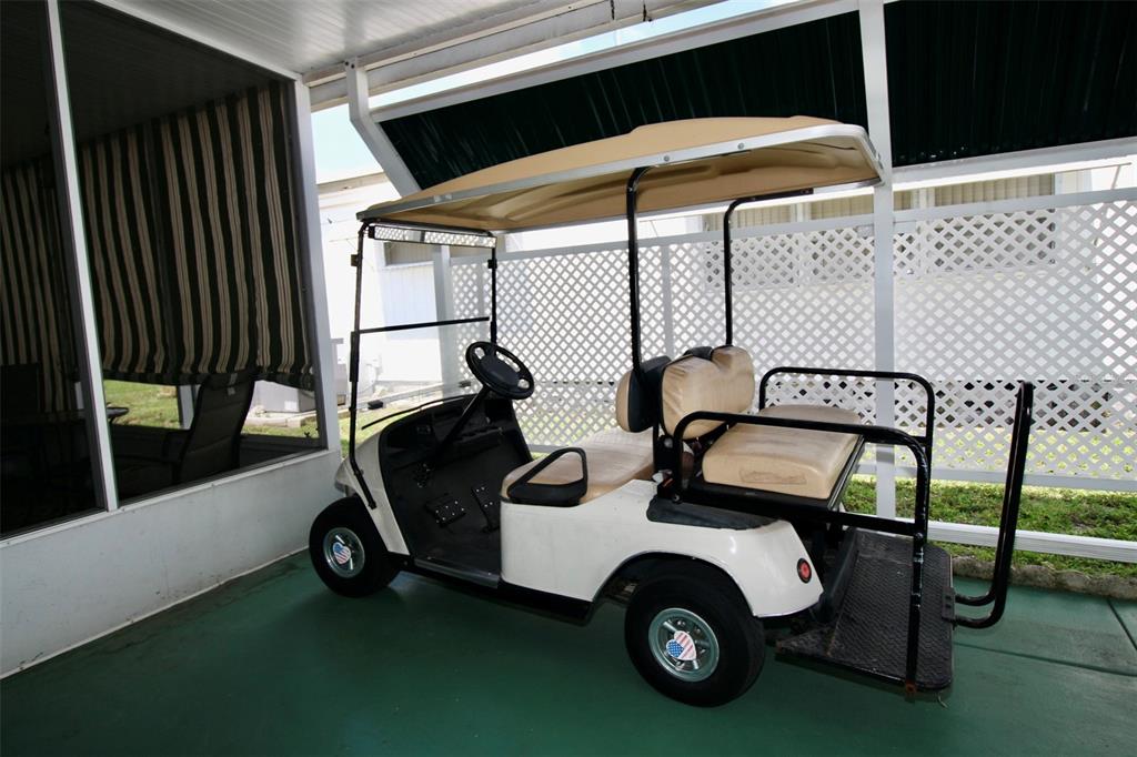 A white golf cart with a tan roof is parked on a covered patio — 82292 2ND AVENUE N UNIT 292, PINELLAS PARK, FL