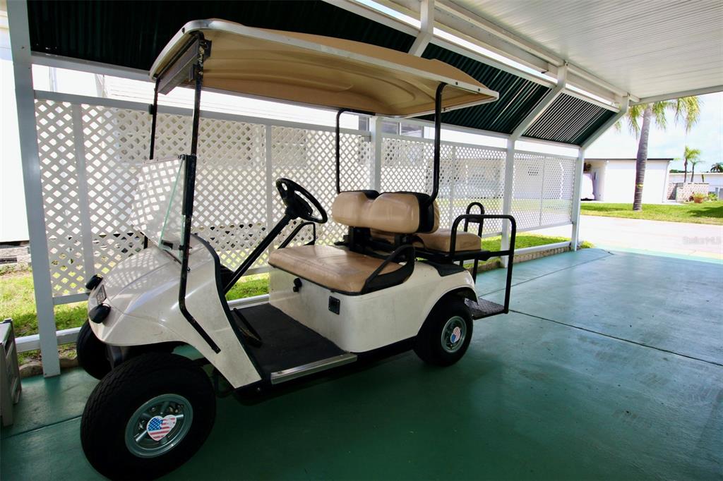 A white golf cart is parked under a covered carport with white lattice fencing — 82292 2ND AVENUE N UNIT 292, PINELLAS PARK, FL