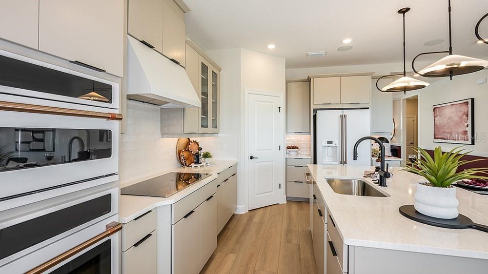 A modern kitchen features light-colored cabinetry, stainless steel appliances, a center island, and wood flooring — 17806 SEDONA STREET, WINTER GARDEN, FL