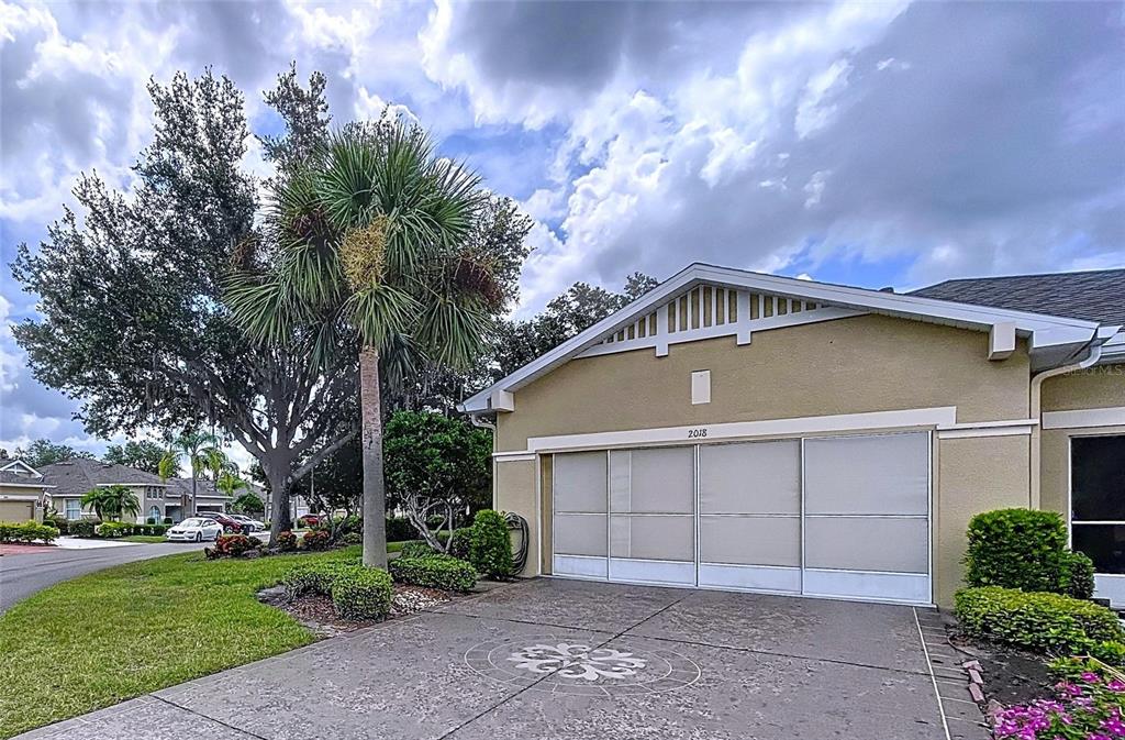 A house exterior features a garage with a screen door and a decorative concrete driveway — 2018 INVERNESS GREENS DRIVE UNIT 2018, SUN CITY CENTER, FL