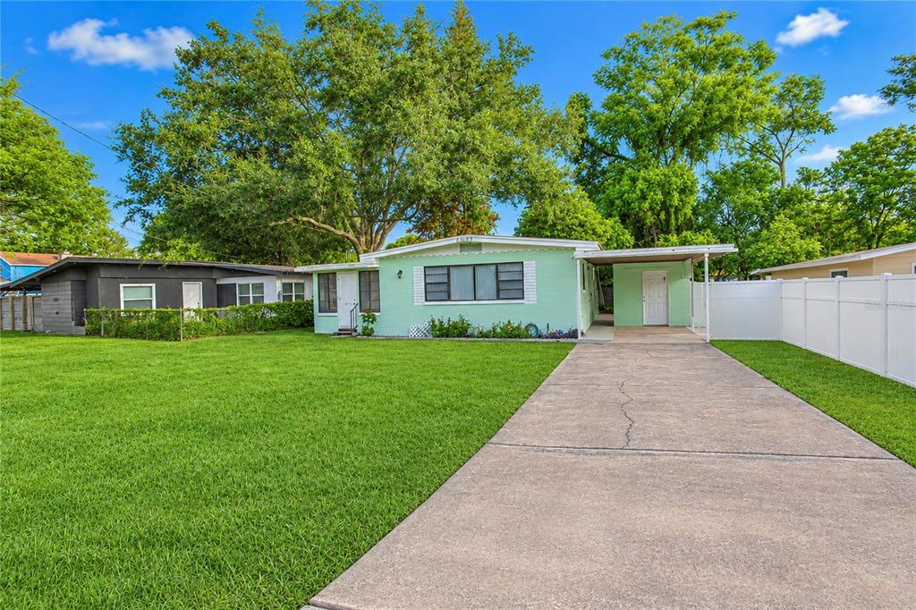 A light green single-story house features a concrete driveway and a white vinyl fence — 4205 MIZELL STREET, ORLANDO, FL
