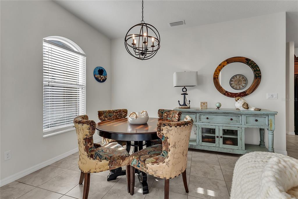 A dining room features a round wooden table, patterned chairs, and a light blue sideboard — 113 ARENA LAKE DRIVE, PALM COAST, FL
