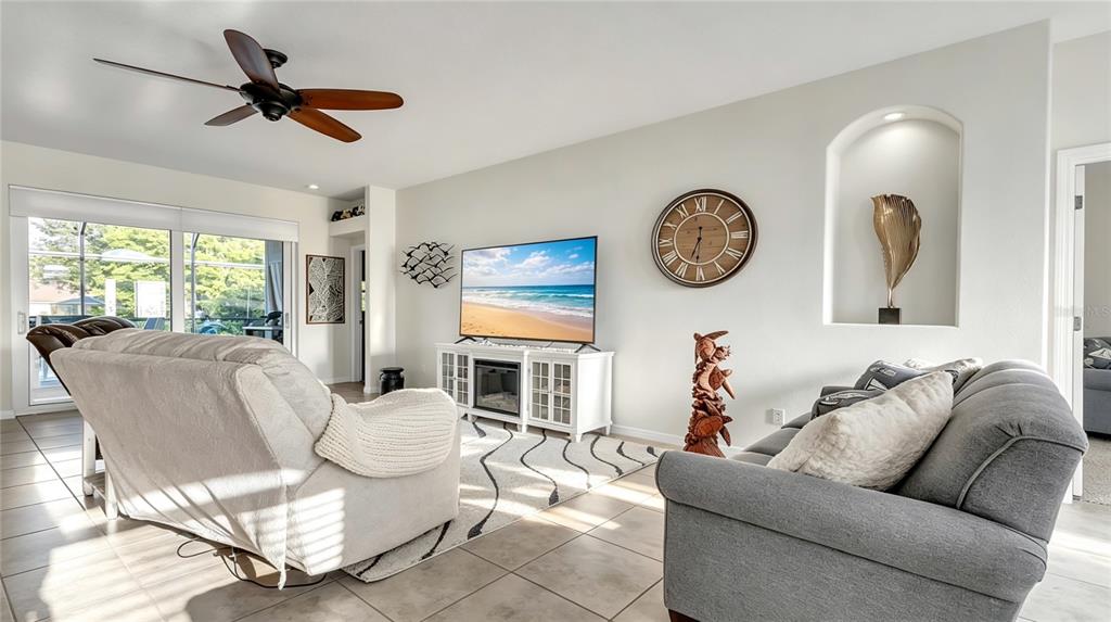 A living room features a television, a large wall clock, and a recessed wall niche — 113 ARENA LAKE DRIVE, PALM COAST, FL