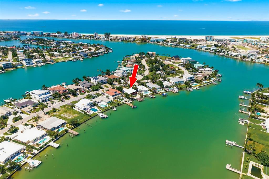 An aerial view shows a waterfront house with a red arrow pointing to its roof — 31 DOLPHIN DRIVE, TREASURE ISLAND, FL