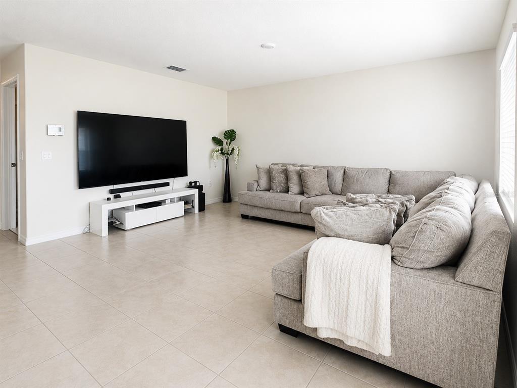 A living room features a large sectional sofa, a wall-mounted television, and light tile flooring — 452 TAYLOR GROVES DRIVE, LAKE WALES, FL