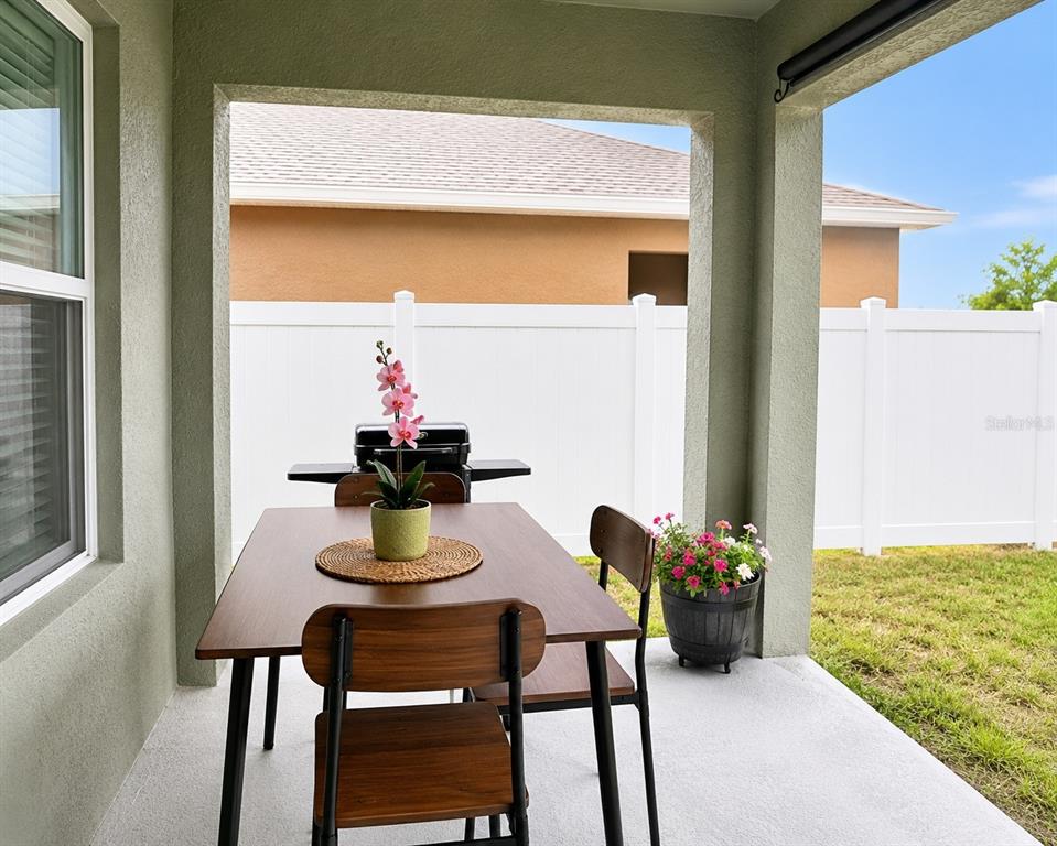 A covered patio features a dining table with chairs, a grill, and a potted plant — 452 TAYLOR GROVES DRIVE, LAKE WALES, FL