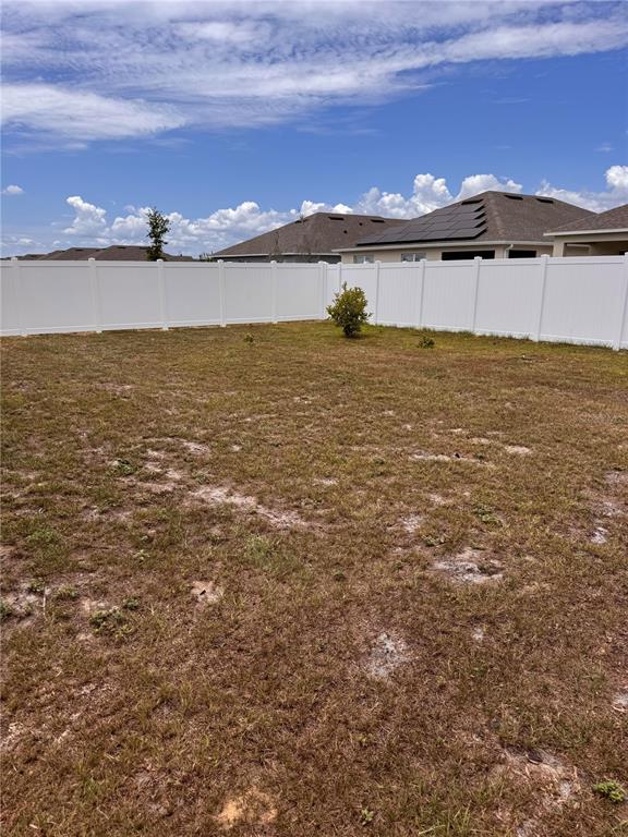 A large, empty backyard features sparse grass and a white vinyl privacy fence — 452 TAYLOR GROVES DRIVE, LAKE WALES, FL