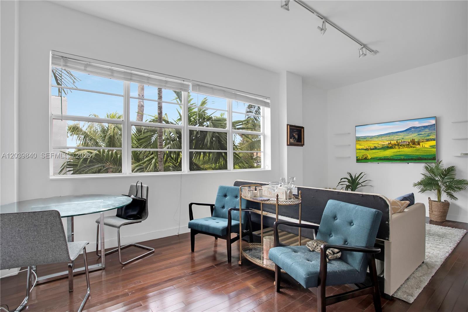 A living room features teal armchairs, a glass dining table, and large windows with palm trees — 935 Euclid Ave # 8, Miami Beach FL 33139, MIAMI BEACH, FL