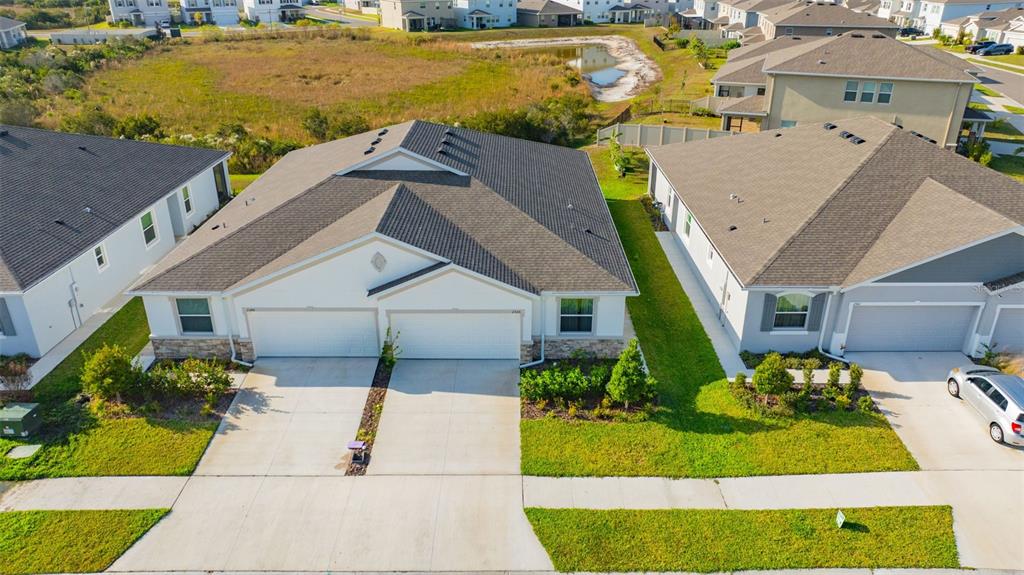 An aerial view shows a suburban house with a gray roof surrounded by green lawns — 2555 BENDING BONSAI DRIVE, WESLEY CHAPEL, FL