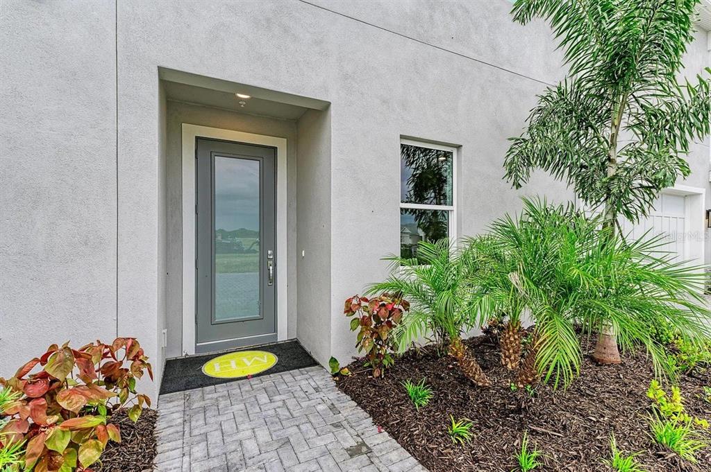 A gray front door with a glass panel sits under a recessed entryway — 10016 REMBRANDT WAY UNIT 102, BRADENTON, FL