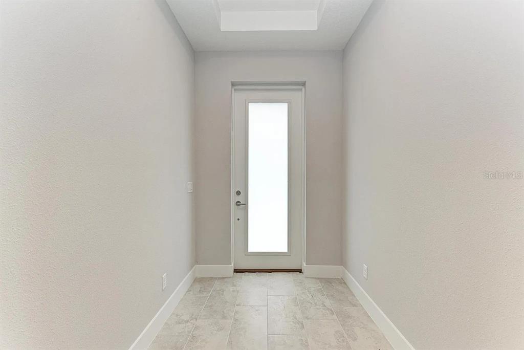 A narrow entryway features light gray walls, white trim, and light-colored rectangular floor tiles — 10016 REMBRANDT WAY UNIT 102, BRADENTON, FL