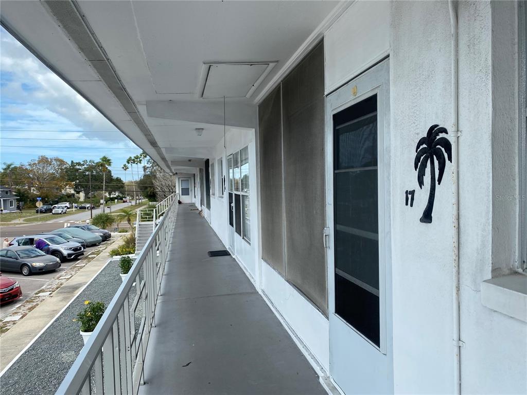An exterior walkway with a metal railing overlooks a parking lot and street — 1221 DREW STREET UNIT A17, CLEARWATER, FL