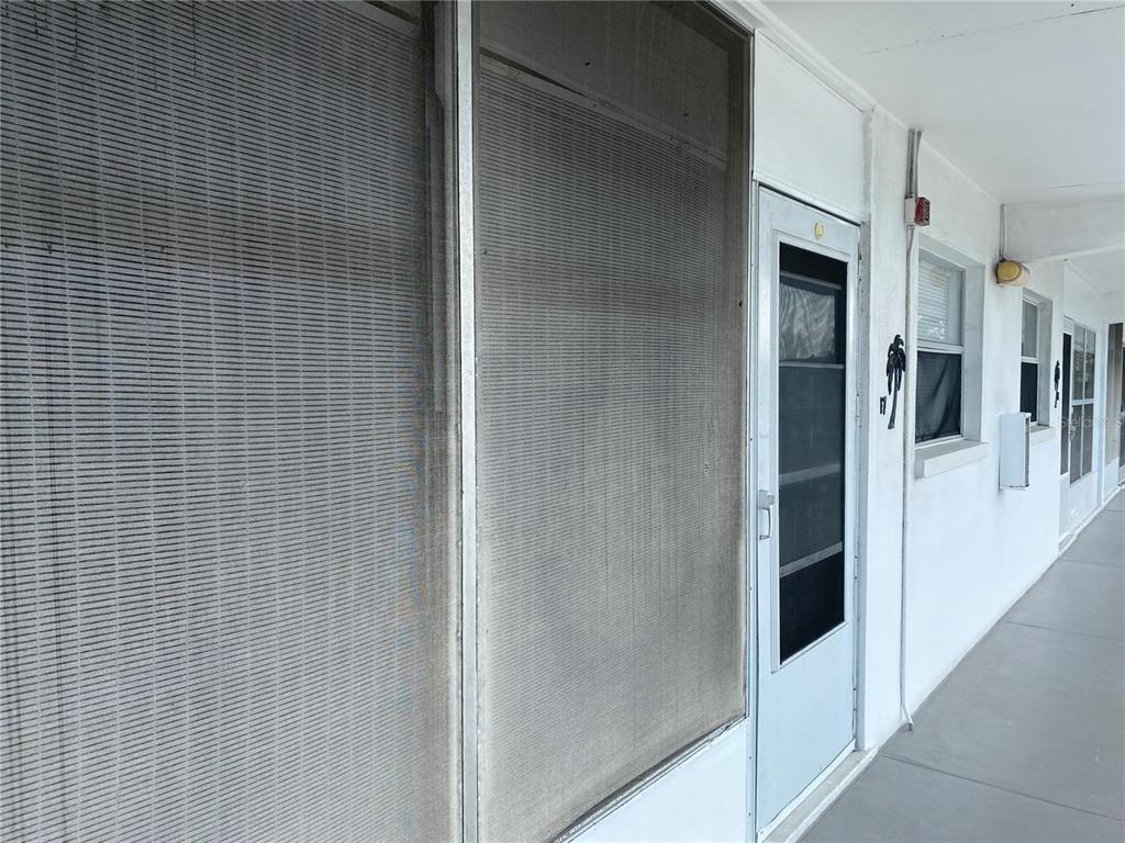 A covered outdoor walkway features a screened-in porch and a white entry door — 1221 DREW STREET UNIT A17, CLEARWATER, FL