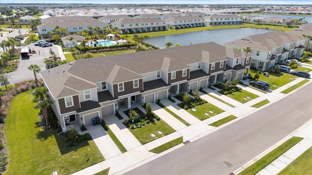 The exterior of a multi-unit townhouse complex features gray siding, garage doors, and small trees — 16632 BERGAMO PLACE, BRADENTON, FL
