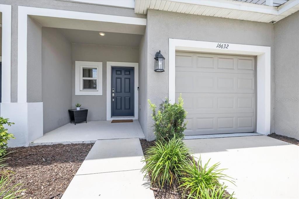 The exterior of a home features a gray front door, a garage, and a walkway — 16632 BERGAMO PLACE, BRADENTON, FL