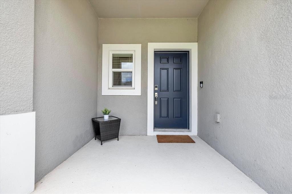 A covered entryway features a dark blue front door, a window, and a small side table — 16632 BERGAMO PLACE, BRADENTON, FL