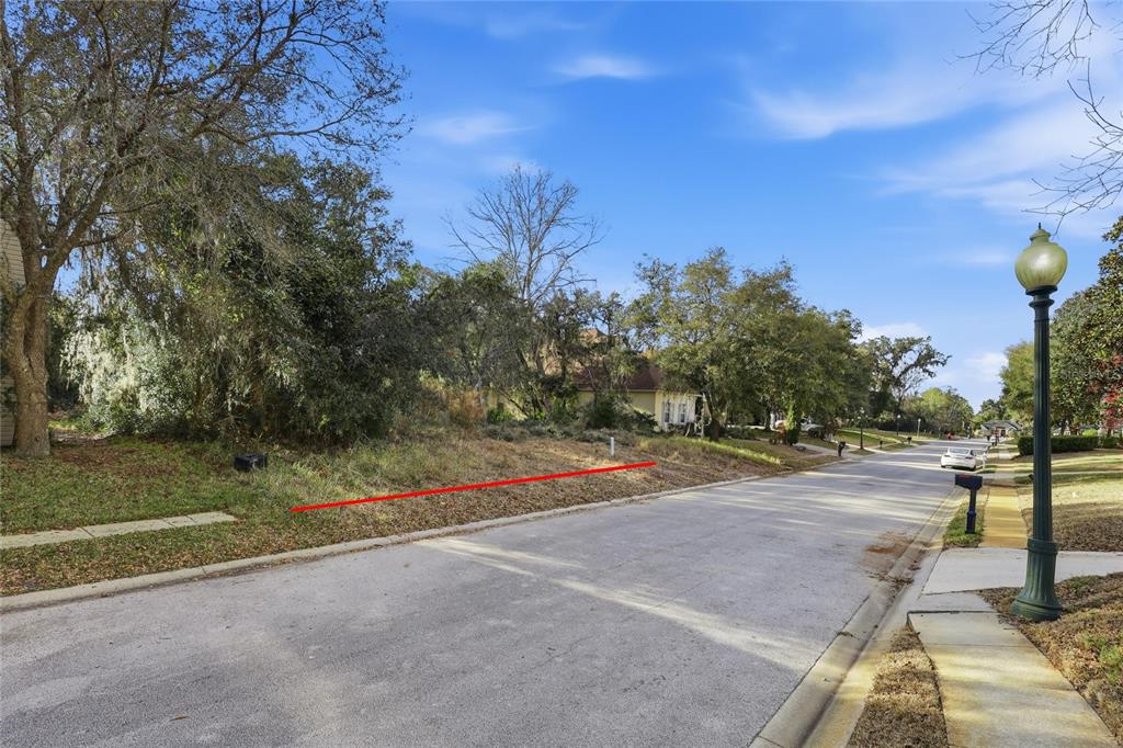 A vacant, tree-covered residential lot sits along a paved street with a decorative lamp post — 7 SAINT CHARLES PLACE, FLAGLER BEACH, FL