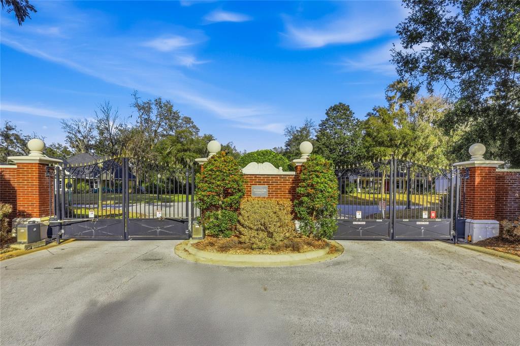 A gated entrance with brick pillars and black metal fencing leads into a residential community — 7 SAINT CHARLES PLACE, FLAGLER BEACH, FL