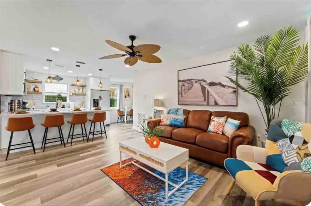 An open-concept living room and kitchen featuring a brown leather sofa and breakfast bar seating — 301 N HOLLYWOOD AVENUE, DAYTONA BEACH, FL