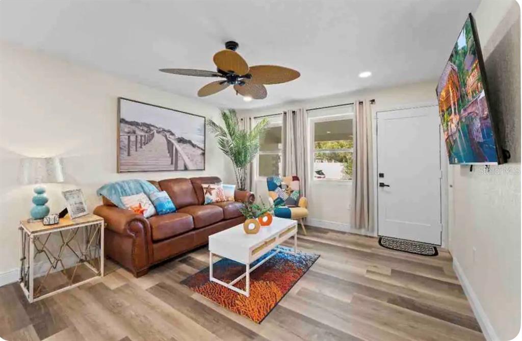 A living room features a brown leather sofa, white coffee table, and wood-look flooring — 301 N HOLLYWOOD AVENUE, DAYTONA BEACH, FL