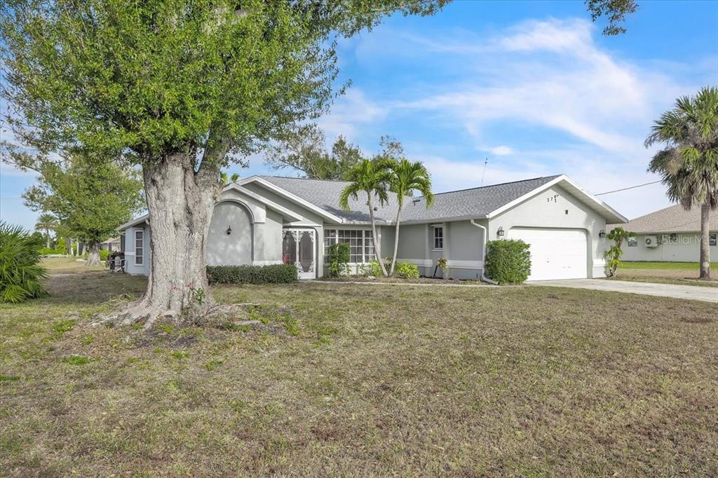 A single-story house with a gray exterior, a two-car garage, and a large front tree — 272 BROADMOOR LANE, ROTONDA WEST, FL