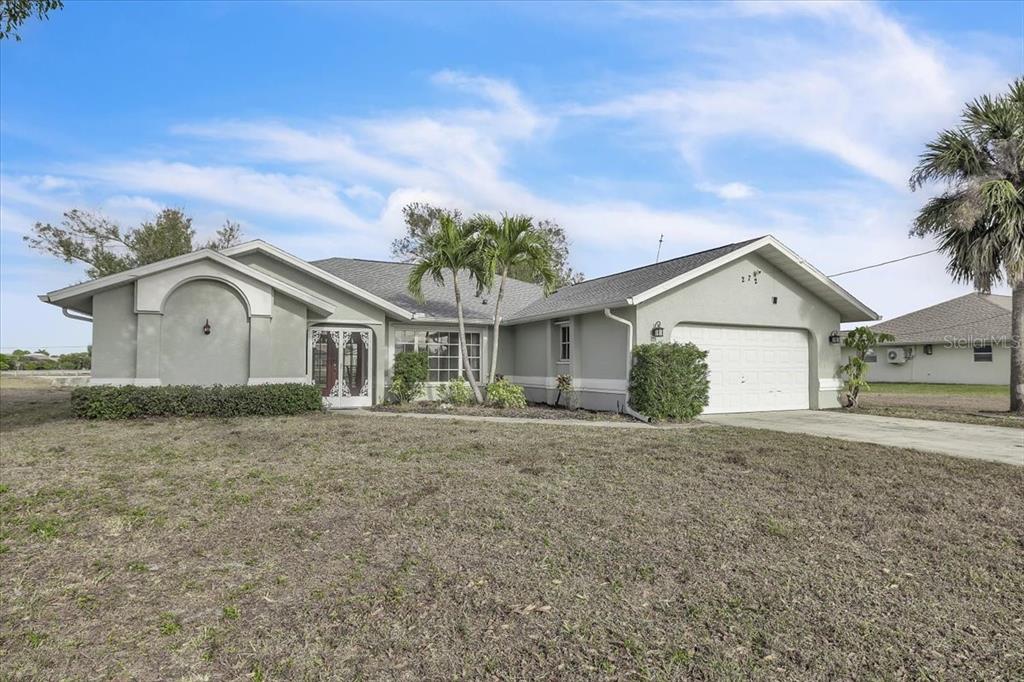 A single-story house with a gray stucco exterior, a two-car garage, and palm trees — 272 BROADMOOR LANE, ROTONDA WEST, FL