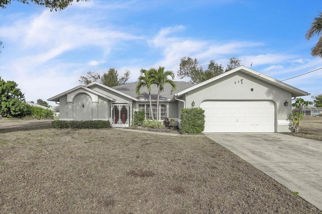 A single-story house with a light gray exterior, a two-car garage, and a palm tree — 272 BROADMOOR LANE, ROTONDA WEST, FL