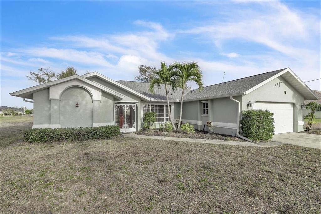 A single-story house with a gray stucco exterior, a two-car garage, and a palm tree — 272 BROADMOOR LANE, ROTONDA WEST, FL