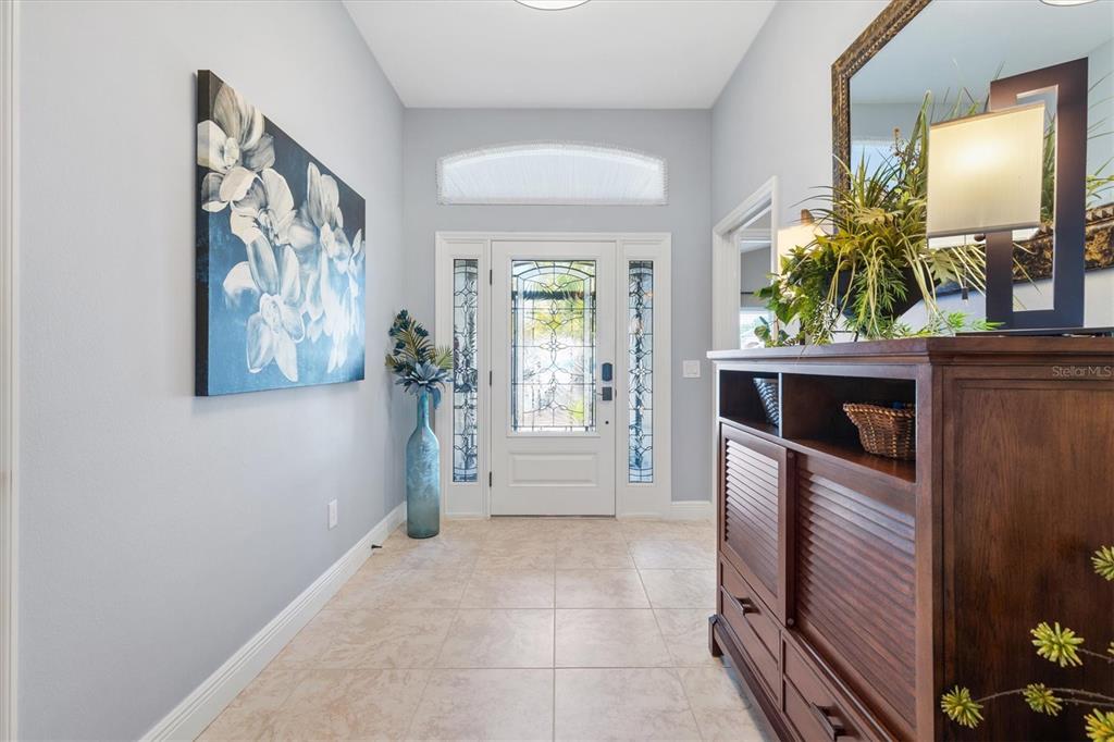 An entryway features light blue walls, tile flooring, a wooden console table, and a front door — 562 BRADFORD LOOP, THE VILLAGES, FL