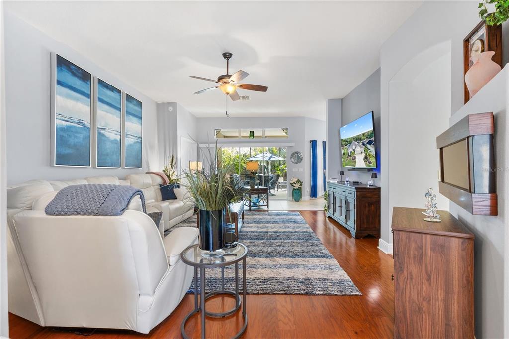 A living room features white leather furniture, a blue area rug, and hardwood floors — 562 BRADFORD LOOP, THE VILLAGES, FL