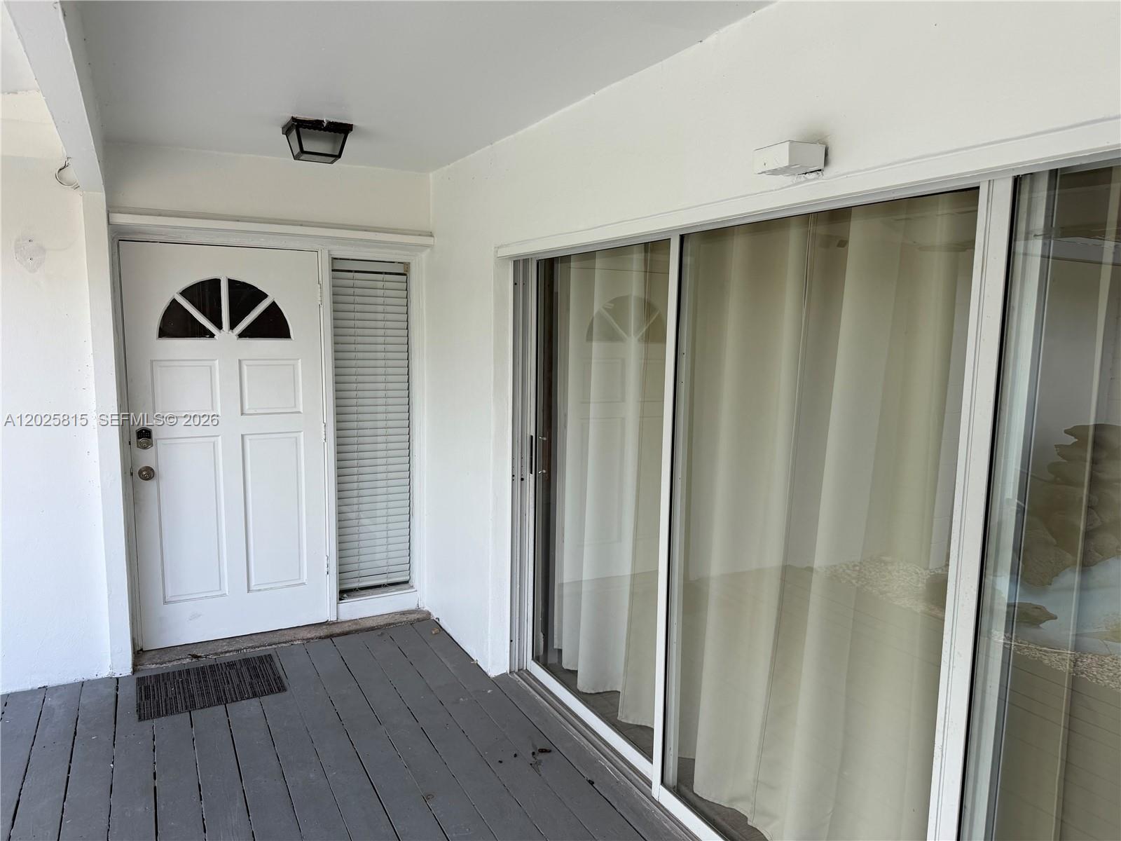 A white front door with a sidelight sits next to a sliding glass door — 19640 Lenaire Dr, Cutler Bay FL 33157, CUTLER BAY, FL