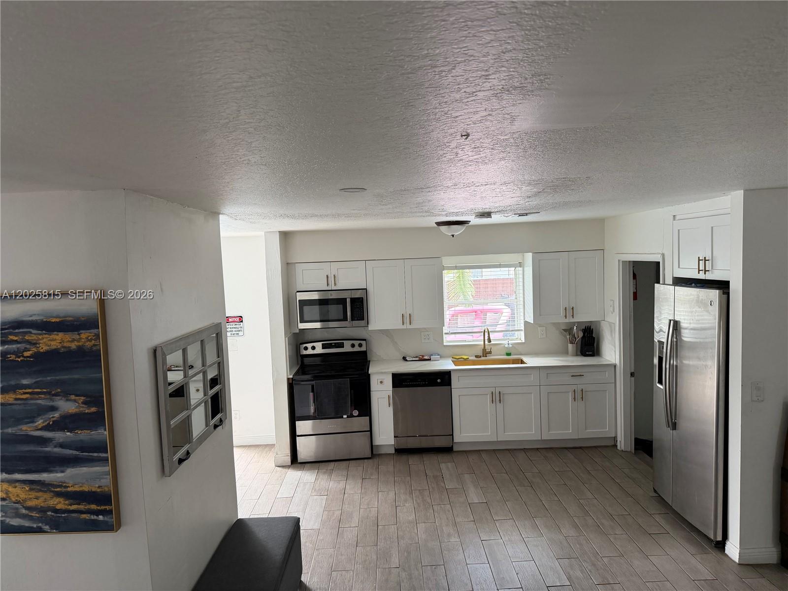 A kitchen features white cabinets, stainless steel appliances, and light-colored wood-look tile flooring — 19640 Lenaire Dr, Cutler Bay FL 33157, CUTLER BAY, FL