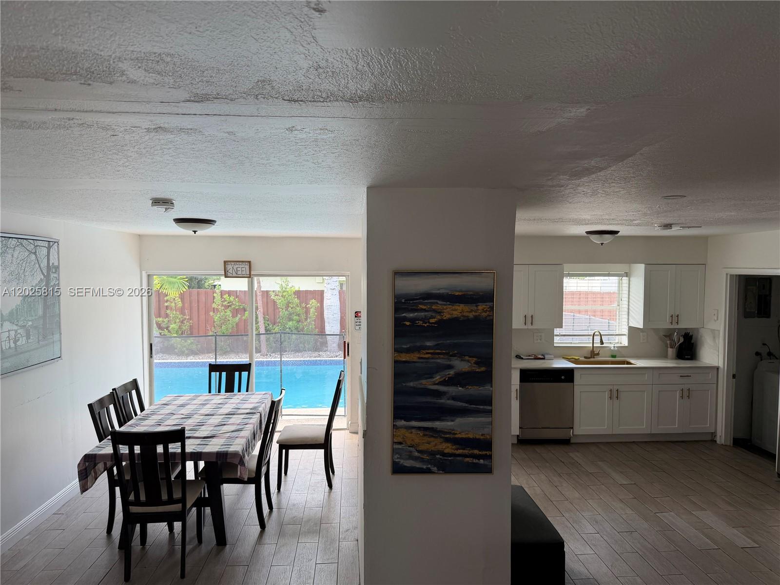 A dining area with a pool view sits adjacent to a kitchen with white cabinets — 19640 Lenaire Dr, Cutler Bay FL 33157, CUTLER BAY, FL
