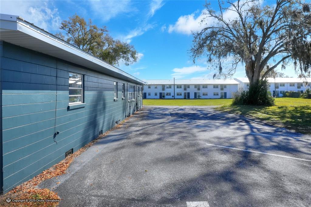 An exterior view shows a blue building side next to a parking lot and apartments — 300 1ST STREET S, WINTER HAVEN, FL