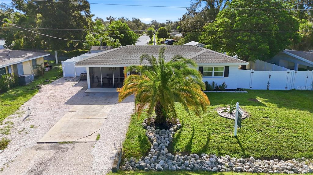 A modern kitchen features white cabinets, stainless steel appliances, a gold chandelier, and light flooring — 6103 CARLTON AVENUE, SARASOTA, FL